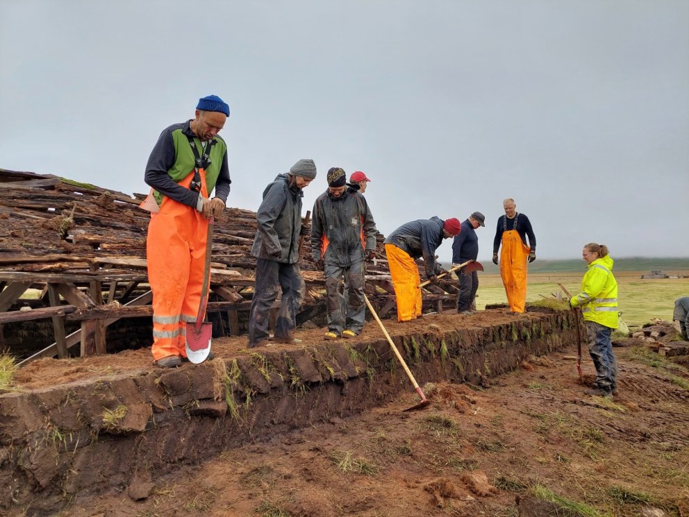 Nemendur og kennarar frá smíðadeild NTNU háskólanum í Þrándheimi í Noregi vinna í vegg á Syðstu-Grun&hellip;